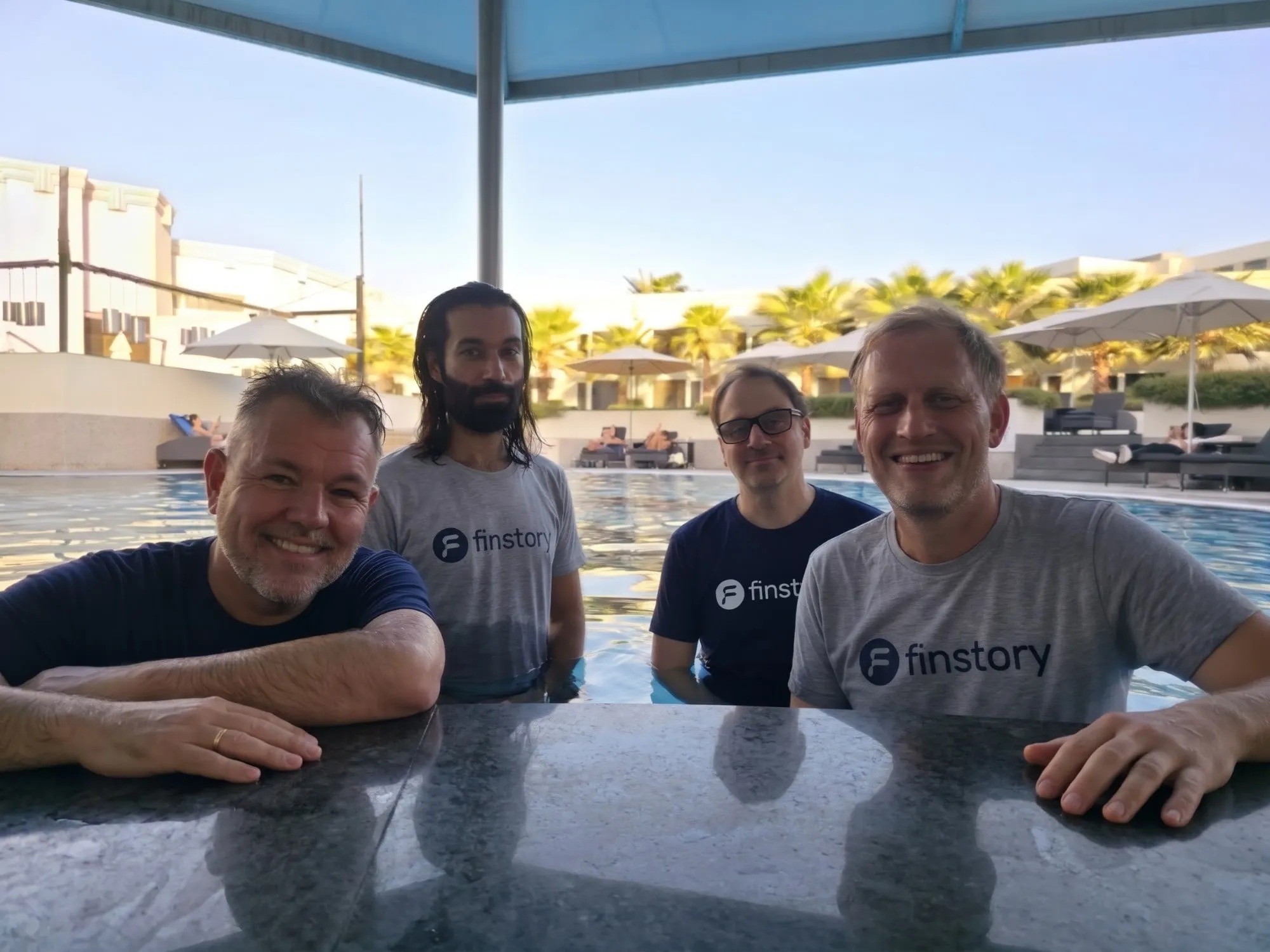 The finstory team in finstory T-shirts at a poolside table