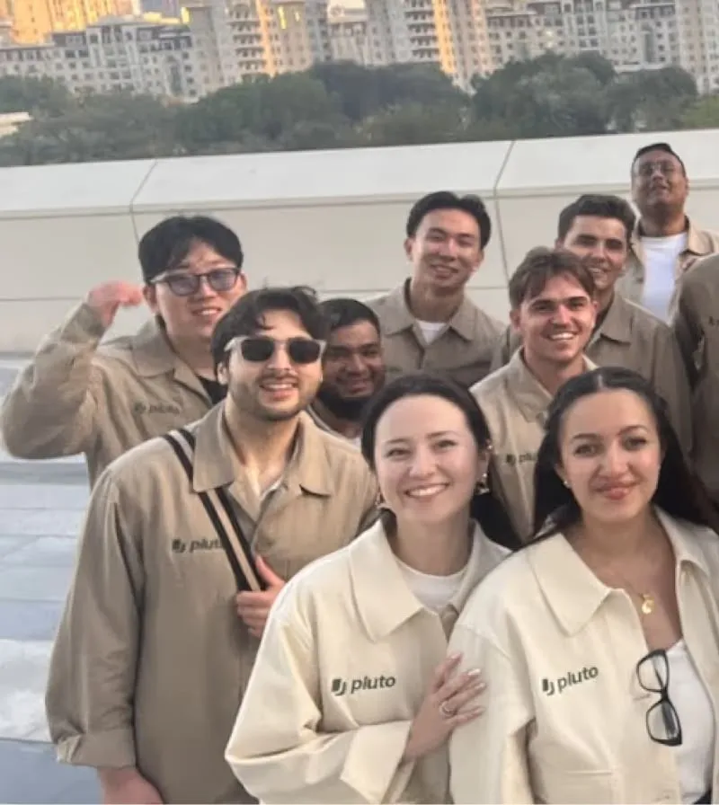 Members of the Pluto team in matching branded jackets on a rooftop